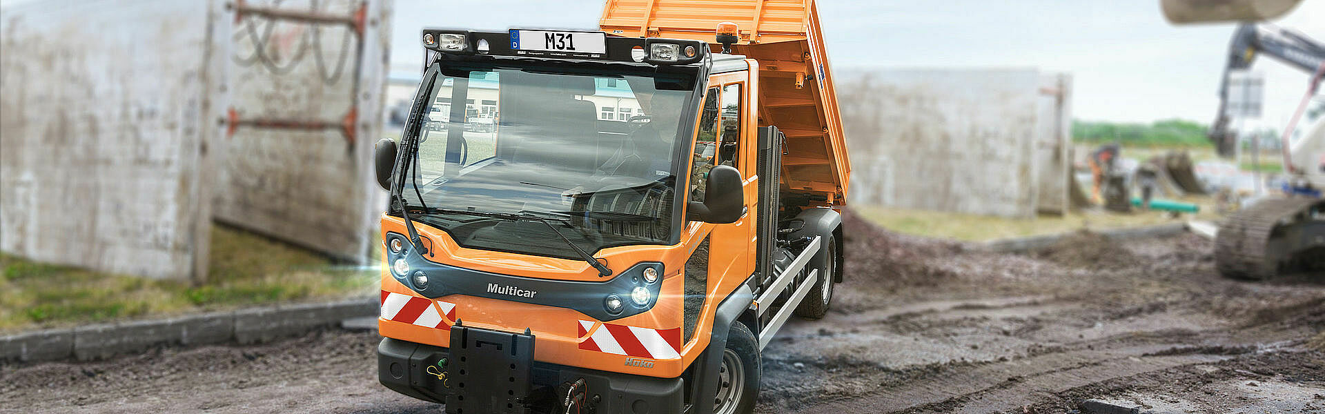 Kommunaler Lasten- und Geräteträger beim Entladen auf einer Baustelle.